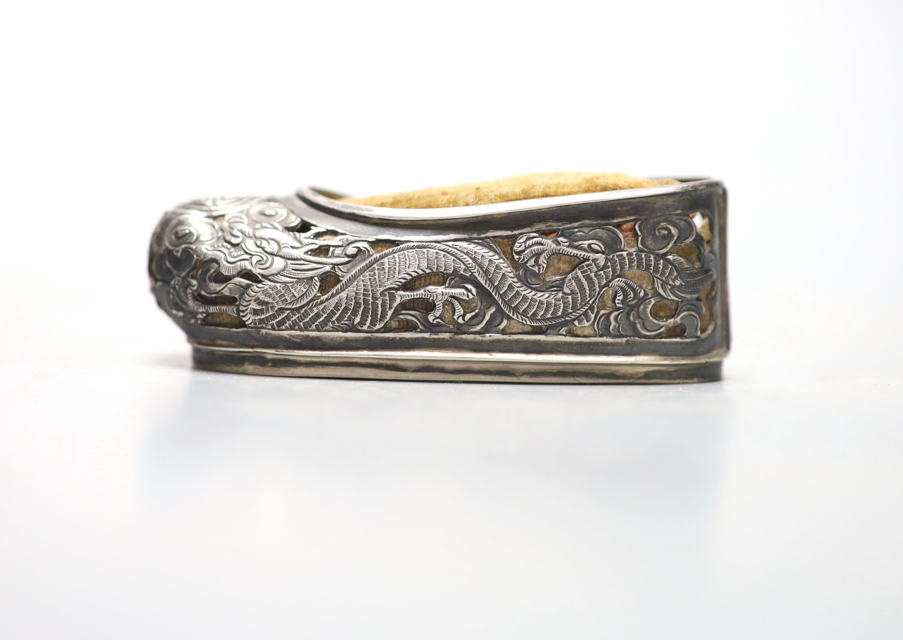 An early 20th century Chinese pierced white metal pin cushion, modelled as a shoe, maker KW, 81mm.